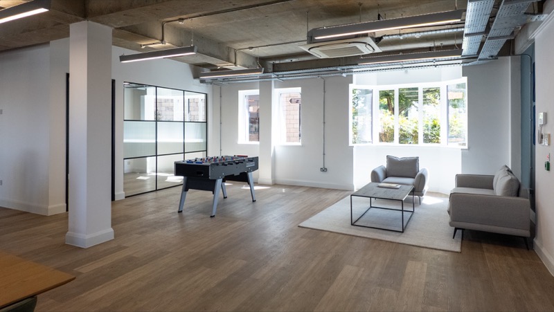Break out area with exposed services, engineered oak flooring, sofas and a table football table