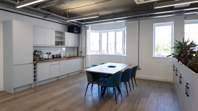 Fitted kitchen and break out space with dining table beneath a bay window