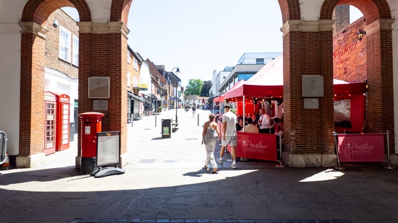 Market stalls glimpsed through a brick archway at Tunsgate